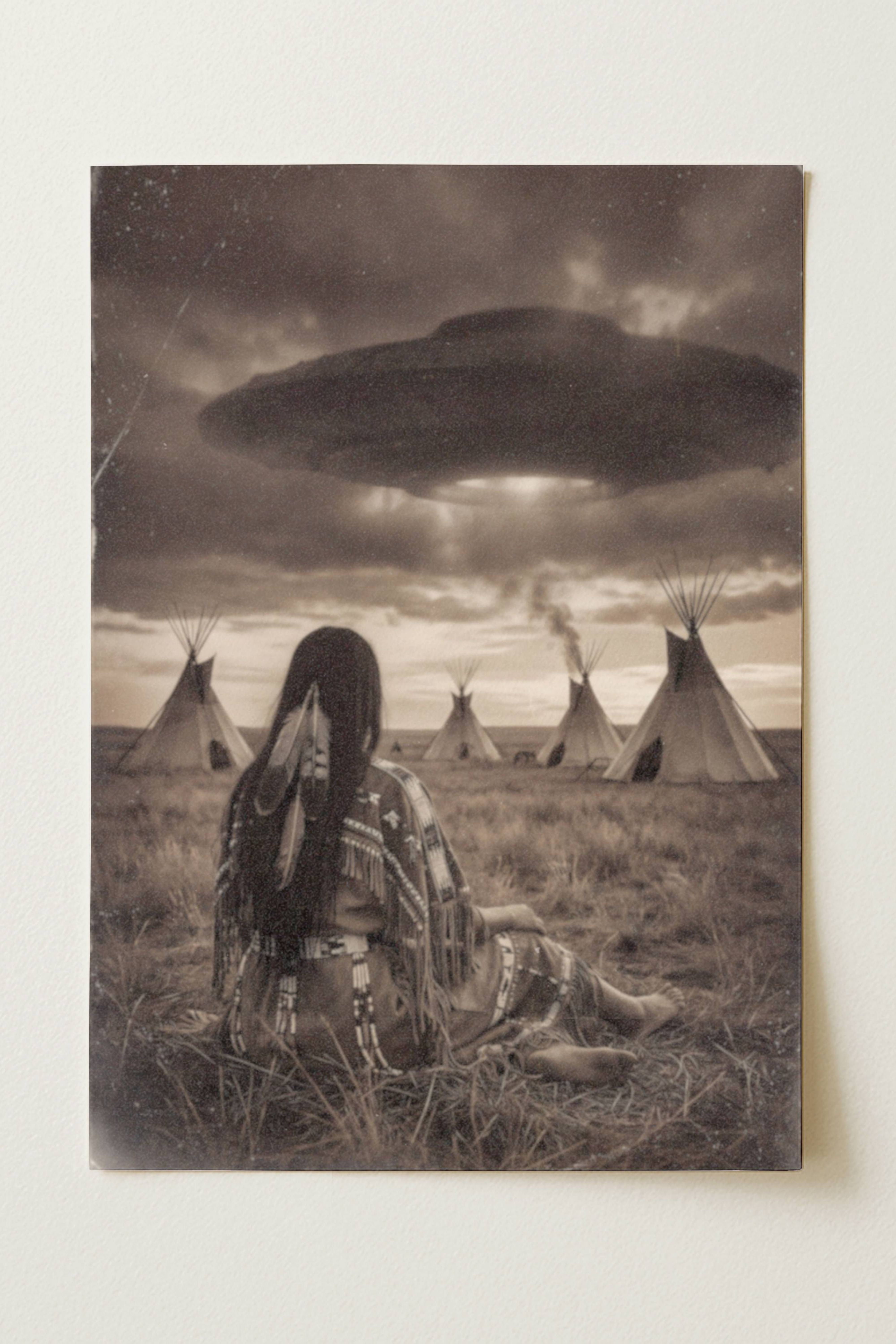Sepia-toned fine art print photographed flat as a sheet of paper, showing a Native American woman seated in a prairie field with her back to the viewer, looking toward a tepee village beneath a massive dark UFO hovering through stormy clouds with a faint beam of light below. The flat lay highlights the vintage aged texture, warm tonal tones and fine detail of this surreal Western art poster printed on premium matte paper.