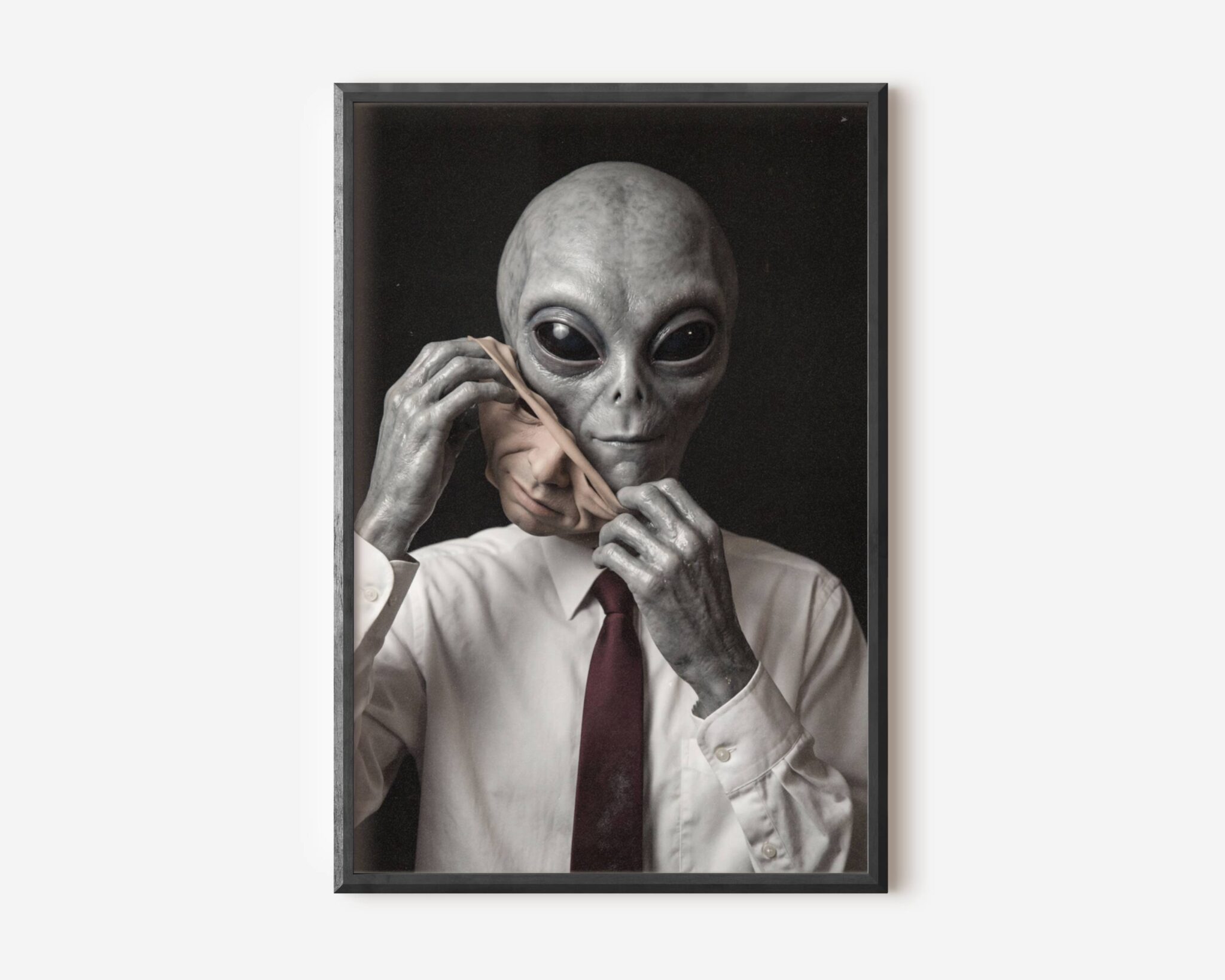 Premium dark concept poster of a grey alien dressed in a white shirt and red tie removing a human face mask, blending corporate satire with dark sci-fi in a striking portrait composition – unframed alien art poster, ufoposter.com