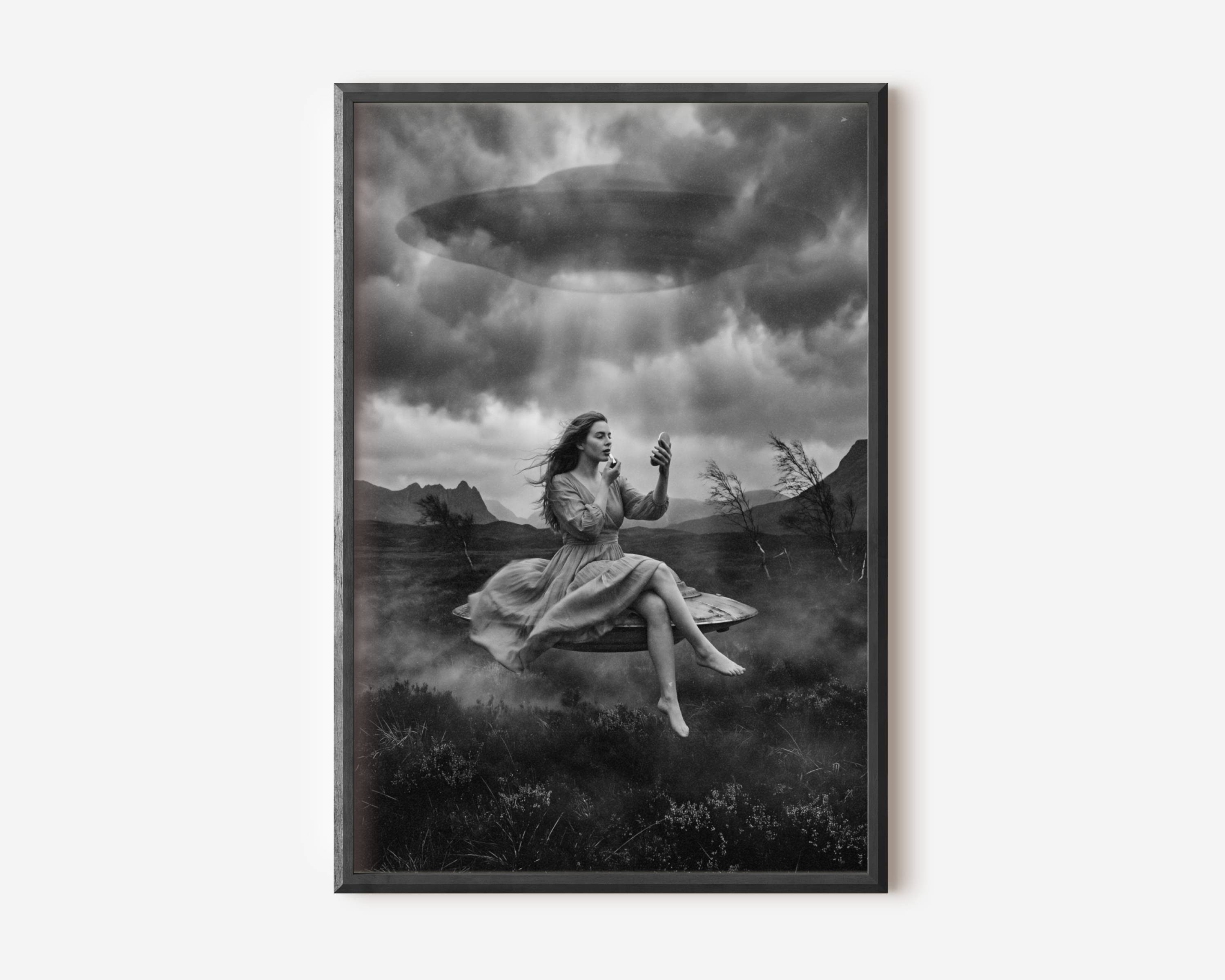 Black and white fine art print of a woman in a flowing dress sitting barefoot on a levitating surface, calmly applying lipstick while looking into a small mirror, as a large UFO hovers above her in a stormy sky over a dark misty landscape. A surreal and darkly humorous cinematic sci-fi wall art print printed on premium matte paper.