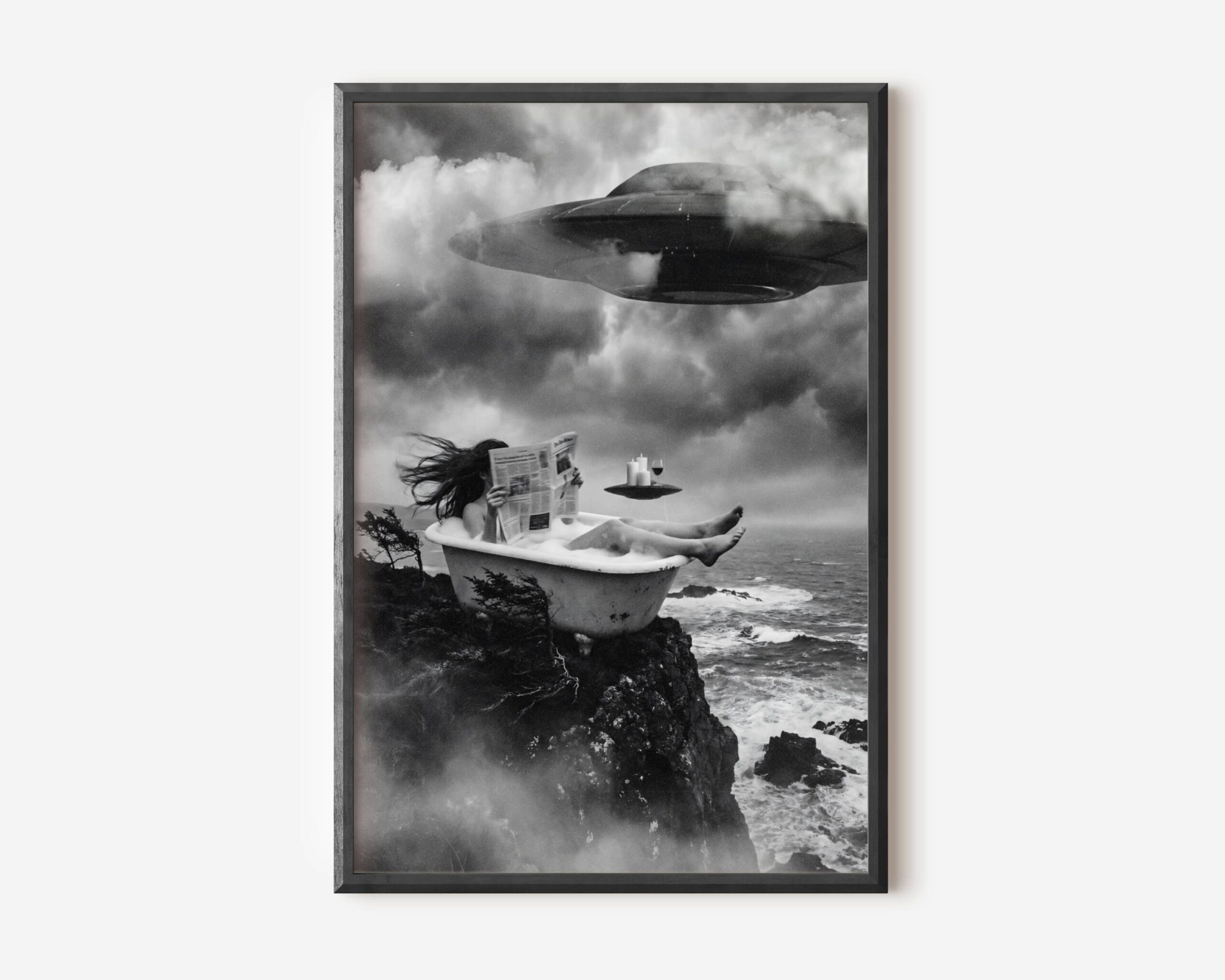 Black and white fine art print of a woman relaxing in a clawfoot bathtub perched on a rocky coastal cliff, reading a newspaper with complete composure as a massive UFO looms through storm clouds above her, while a small flying saucer hovers nearby serving as a tray for candles and a glass of wine. A surreal and darkly humorous cinematic sci-fi wall art print printed on premium matte paper.