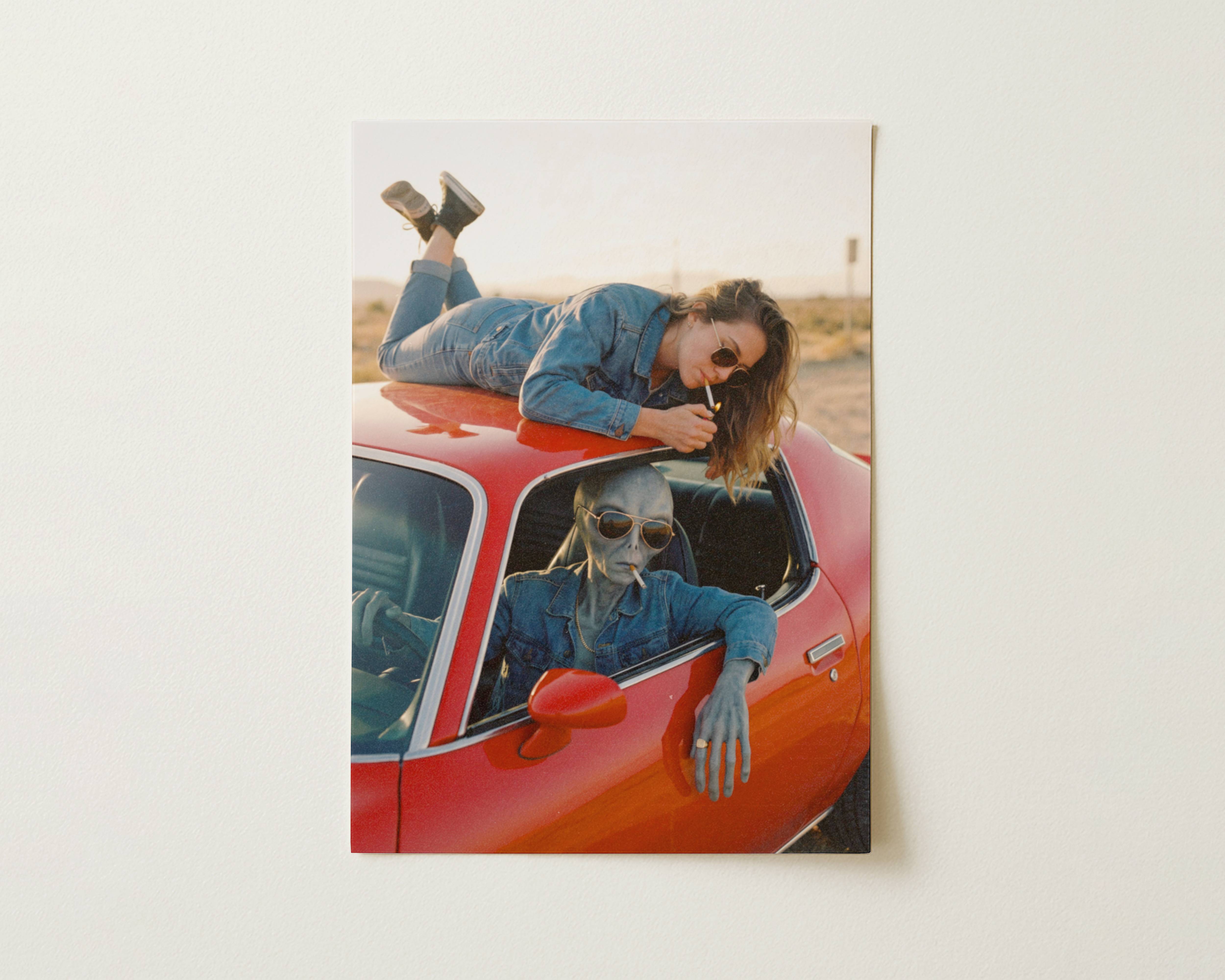 Flat print warm-toned retro artwork of a grey alien driver in sunglasses and a woman in denim sharing cigarettes on a vintage red car parked on an empty desert highway – high quality unframed flat poster print, ufoposter.com