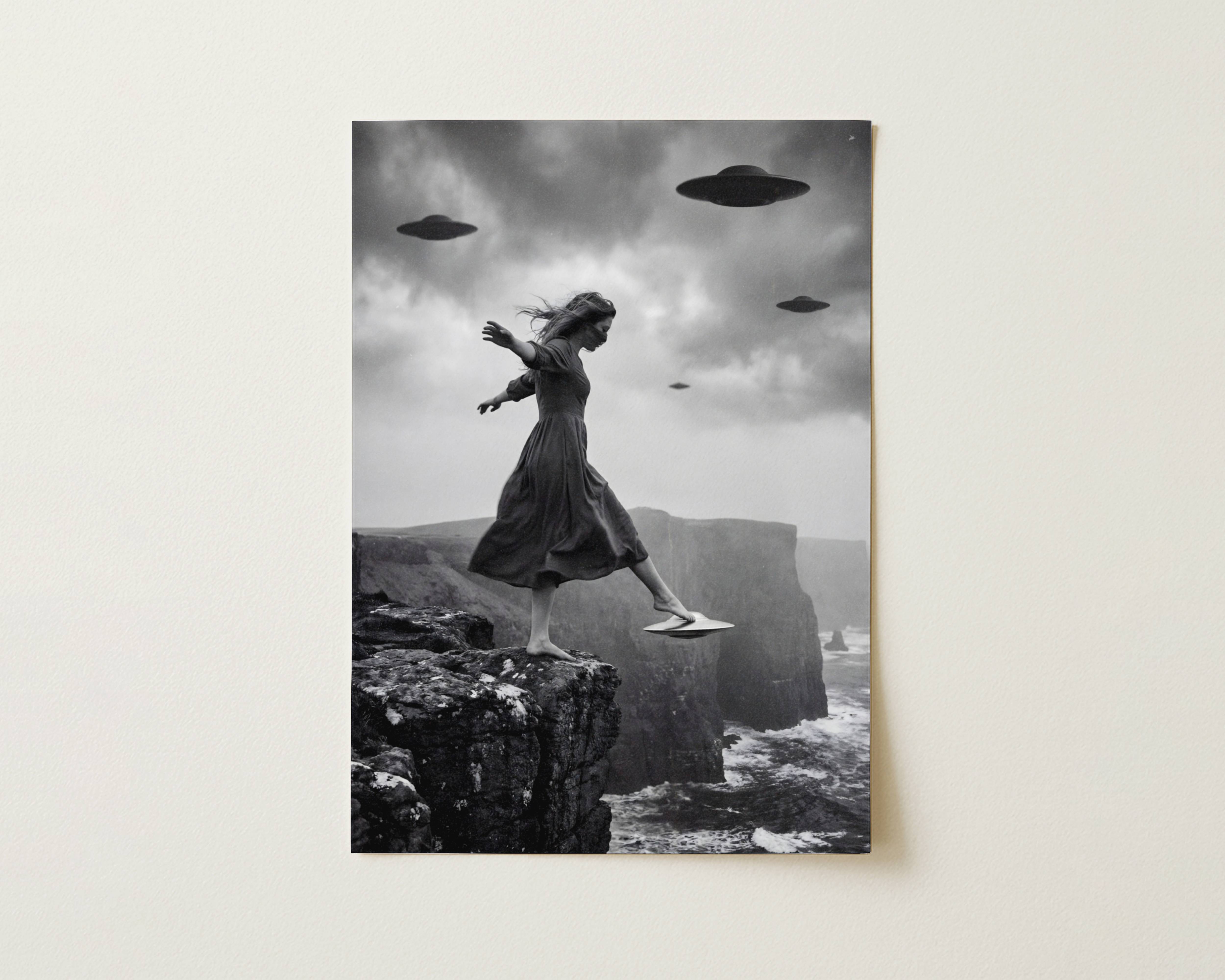 Black and white fine art print photographed flat as a sheet of paper, showing a woman on the edge of a rocky coastal cliff stepping onto a small UFO with three larger spacecraft visible in the dramatic stormy sky above a wild coastline. The flat lay highlights the rich tonal contrast and fine detail of this surreal cinematic art poster.