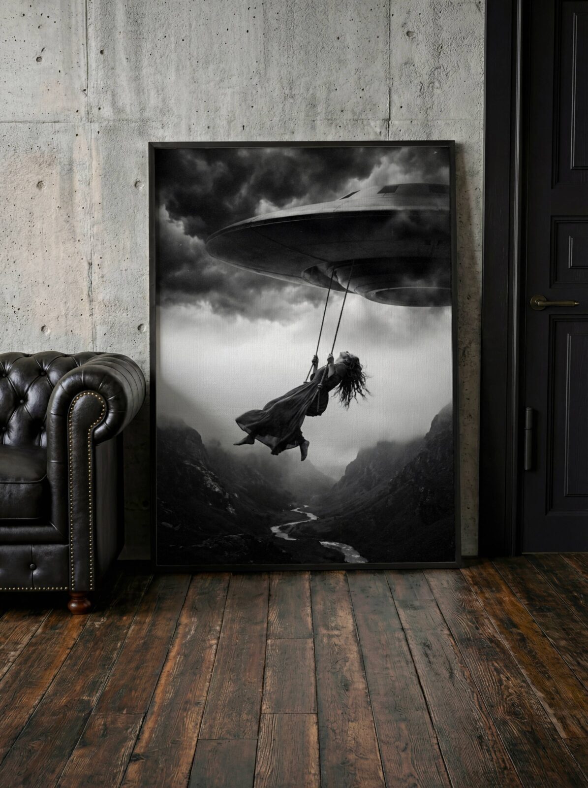 Black and white surreal art print of a woman on a rope swing suspended beneath a UFO over a dramatic canyon landscape, included in a gallery wall arrangement with complementary monochrome prints to create a cohesive and atmospheric fine art display. UFO Swing Woman Art Print – Lifestyle Floor Lean Display