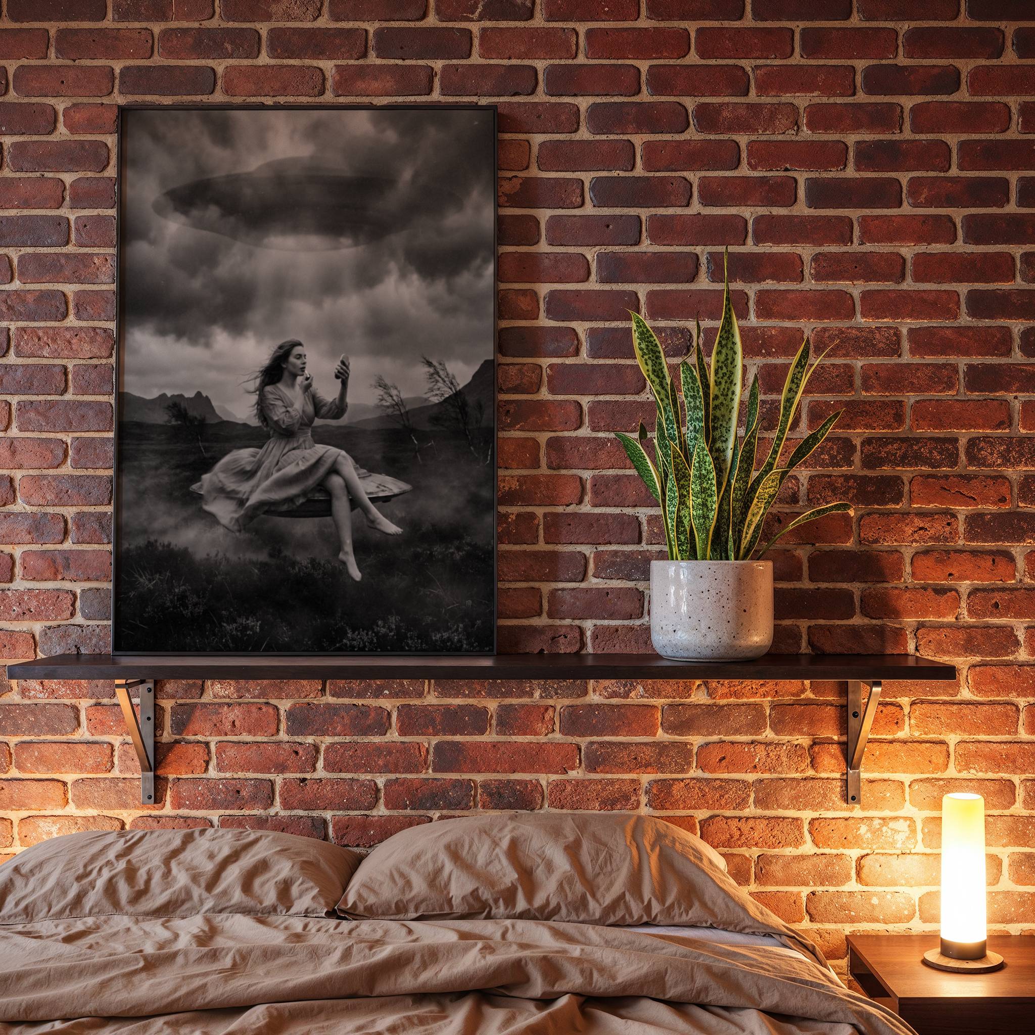 Black and white fine art poster of a barefoot woman in a flowing dress levitating above a dark misty landscape, applying lipstick with quiet composure as a UFO hovers overhead in a dramatic stormy sky, displayed in a bedroom as a striking and surreal piece of wall decoration.