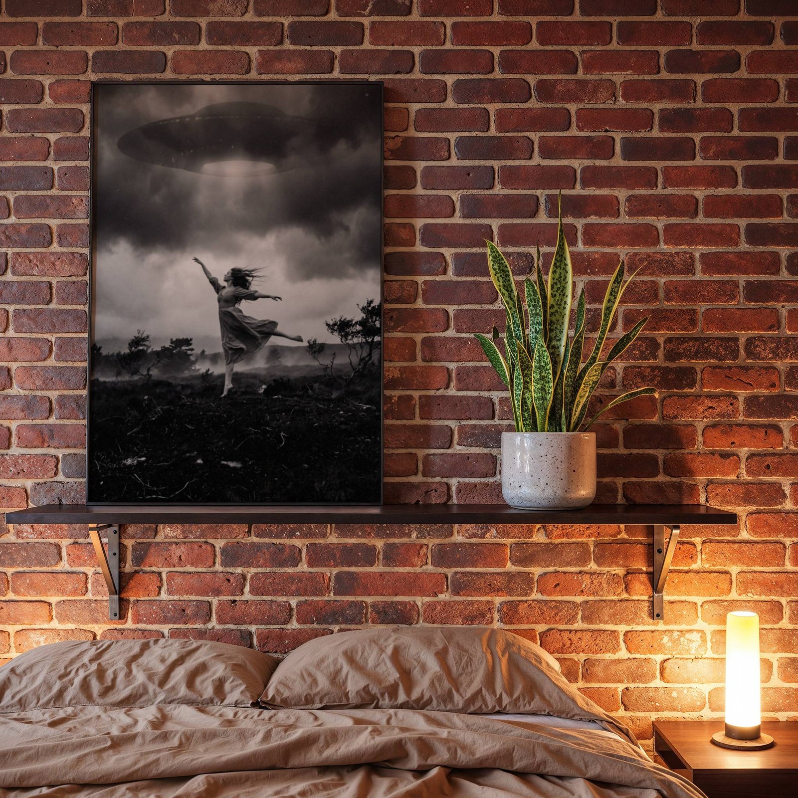 Black and white fine art poster of a barefoot woman in a flowing dress dancing with arms outstretched beneath a large UFO emitting a beam of light through a dramatic stormy sky over a dark moorland, displayed in a bedroom as a striking and atmospheric piece of wall decoration.