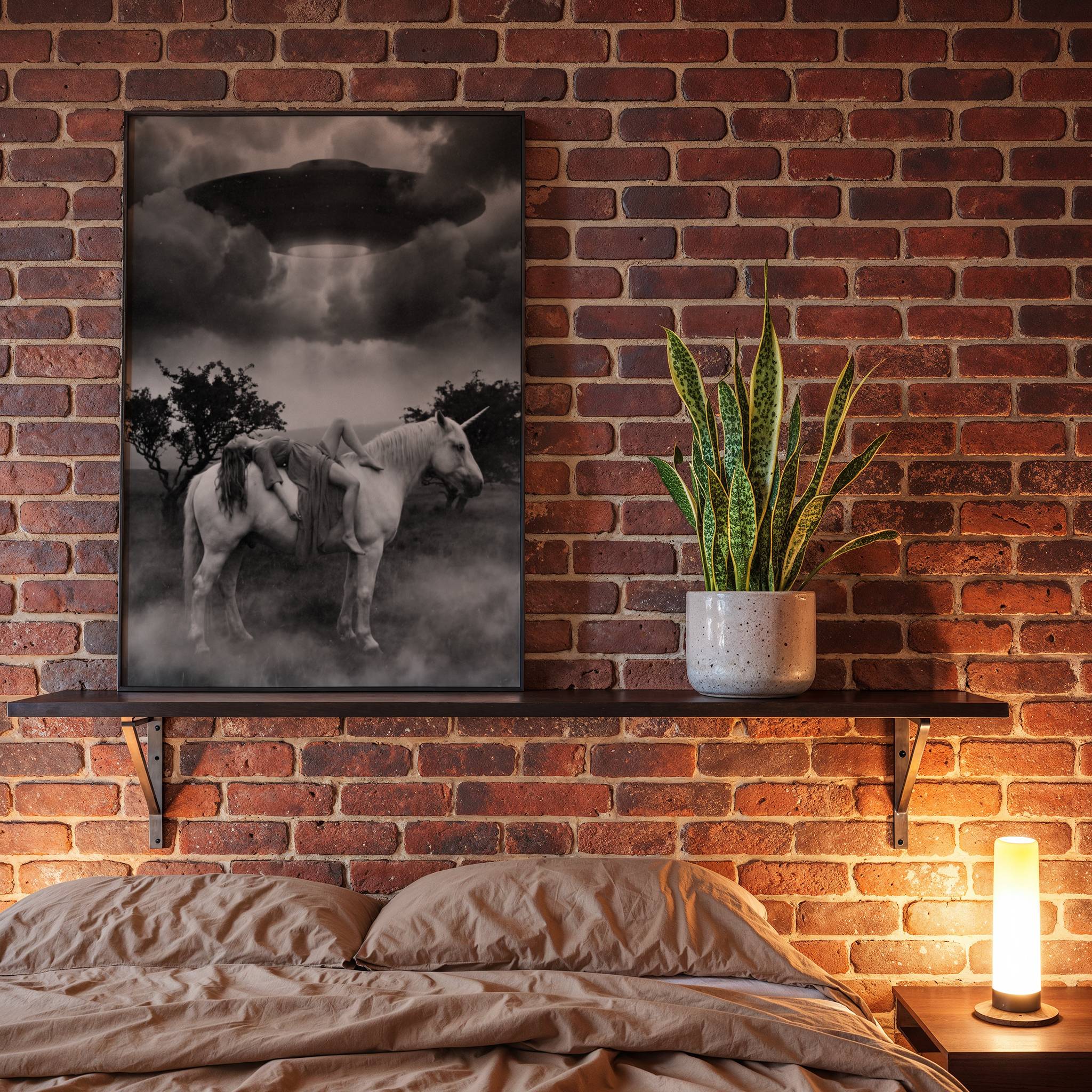 Black and white fine art poster of a woman draped over a white unicorn standing in a foggy landscape as a large UFO looms overhead in a dramatic stormy sky, displayed in a bedroom as a striking and ethereal piece of wall decoration.