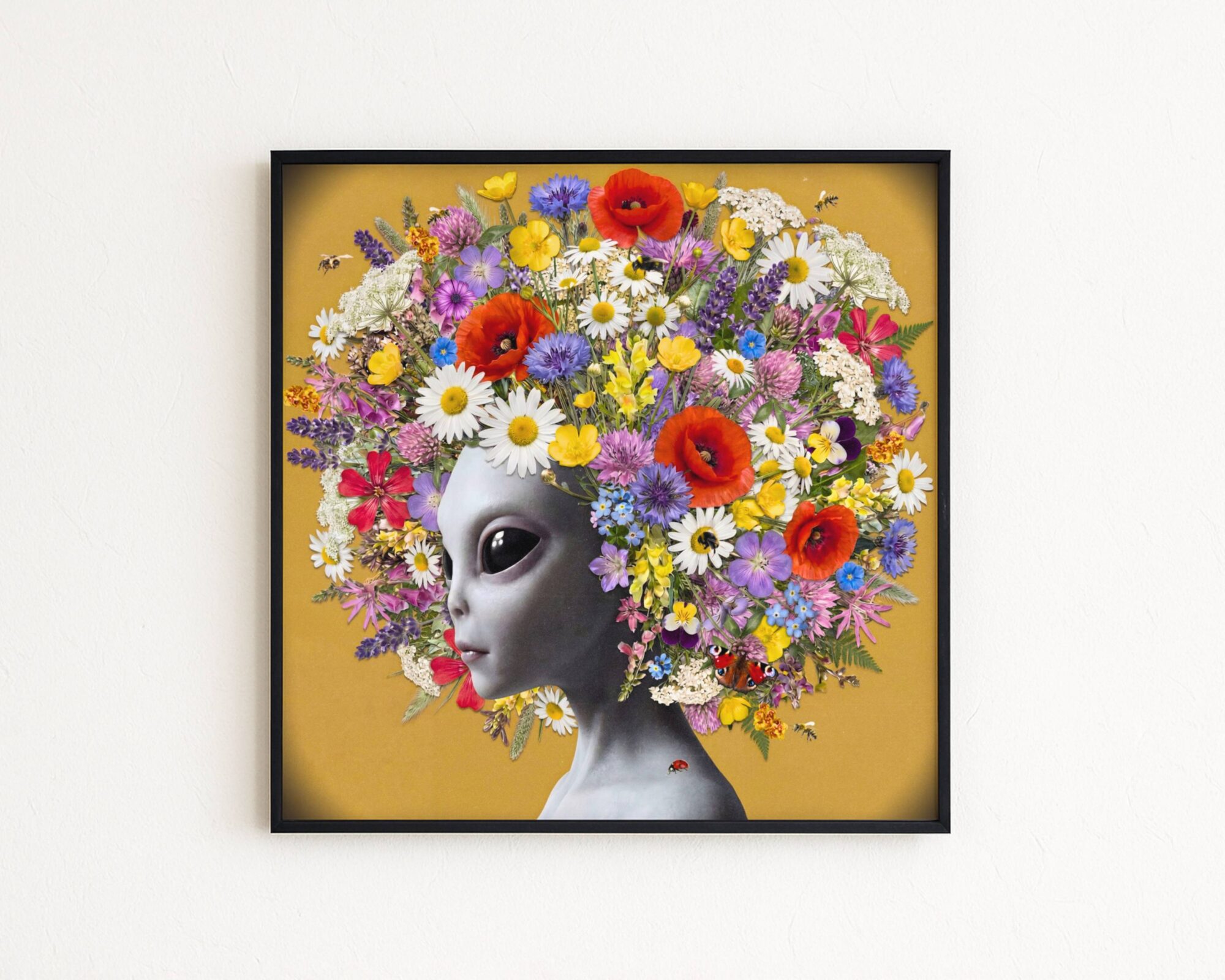 Premium bold surreal portrait of a grey alien gazing softly to one side, crowned with an extraordinary explosion of wildflowers — red poppies, white daisies, purple cornflowers, lavender, forget-me-nots and buttercups — against a warm golden ochre background with bees, a peacock butterfly and a ladybird on her collarbone — a genuinely unique and joyful alien wildflower wall art print – unframed colourful alien art poster, ufoposter.com
