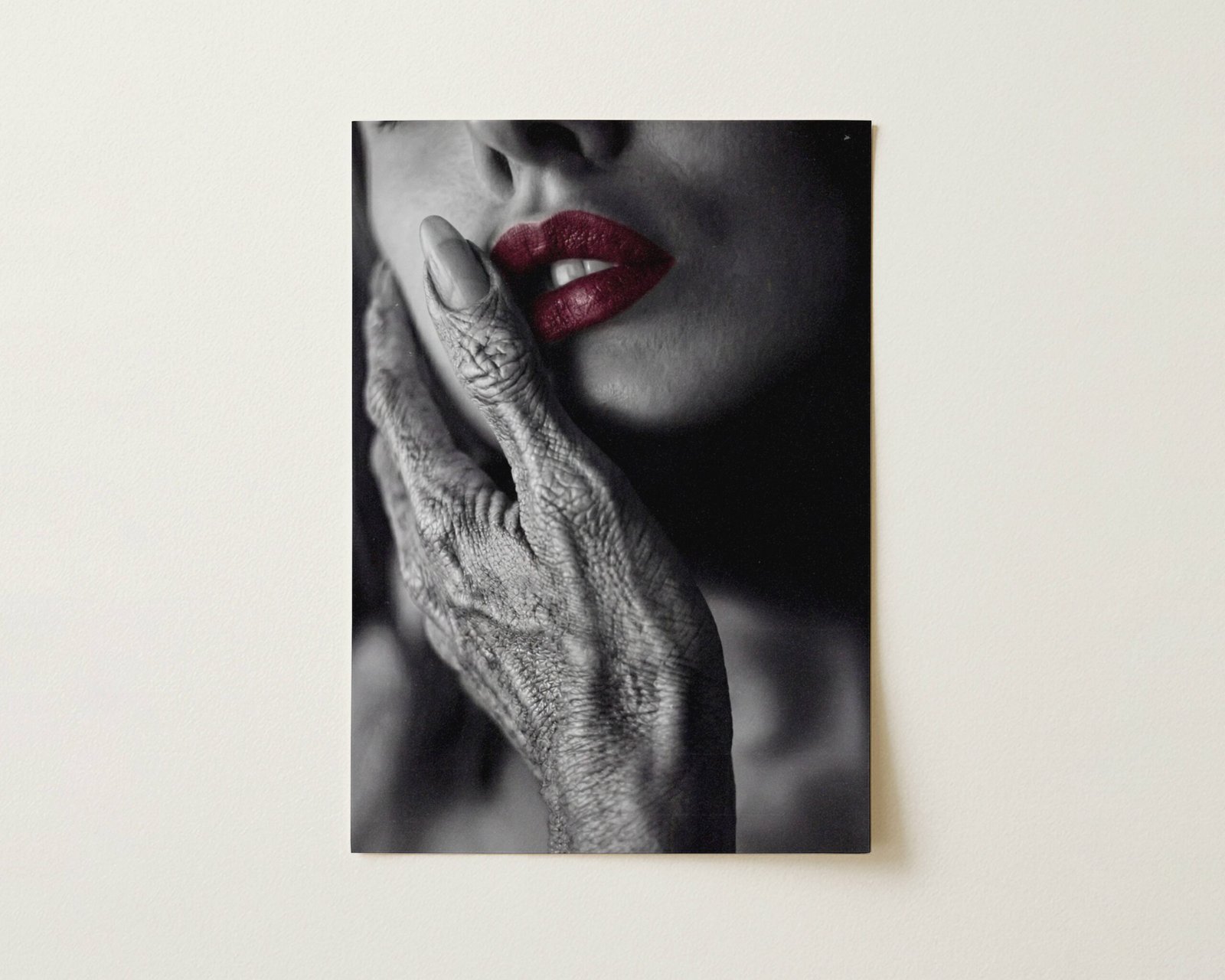 Flat print dark monochrome close-up of a grey alien hand against a woman's cheek with vivid red lips as the sole colour accent in a striking black and white composition — high quality unframed flat poster print, ufoposter.com
