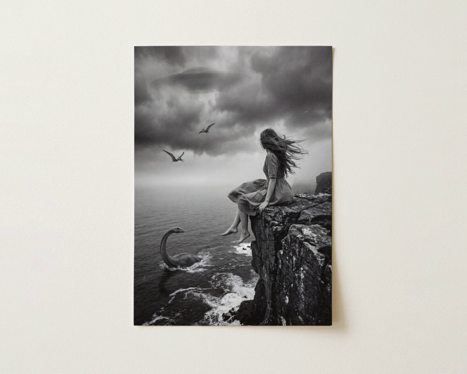 Flat print atmospheric black and white surreal artwork of a barefoot woman on a stormy coastal cliff with a plesiosaur in the crashing waves below, pterodactyls and a UFO in heavy dark storm clouds above — high quality unframed flat poster print, ufoposter.com
