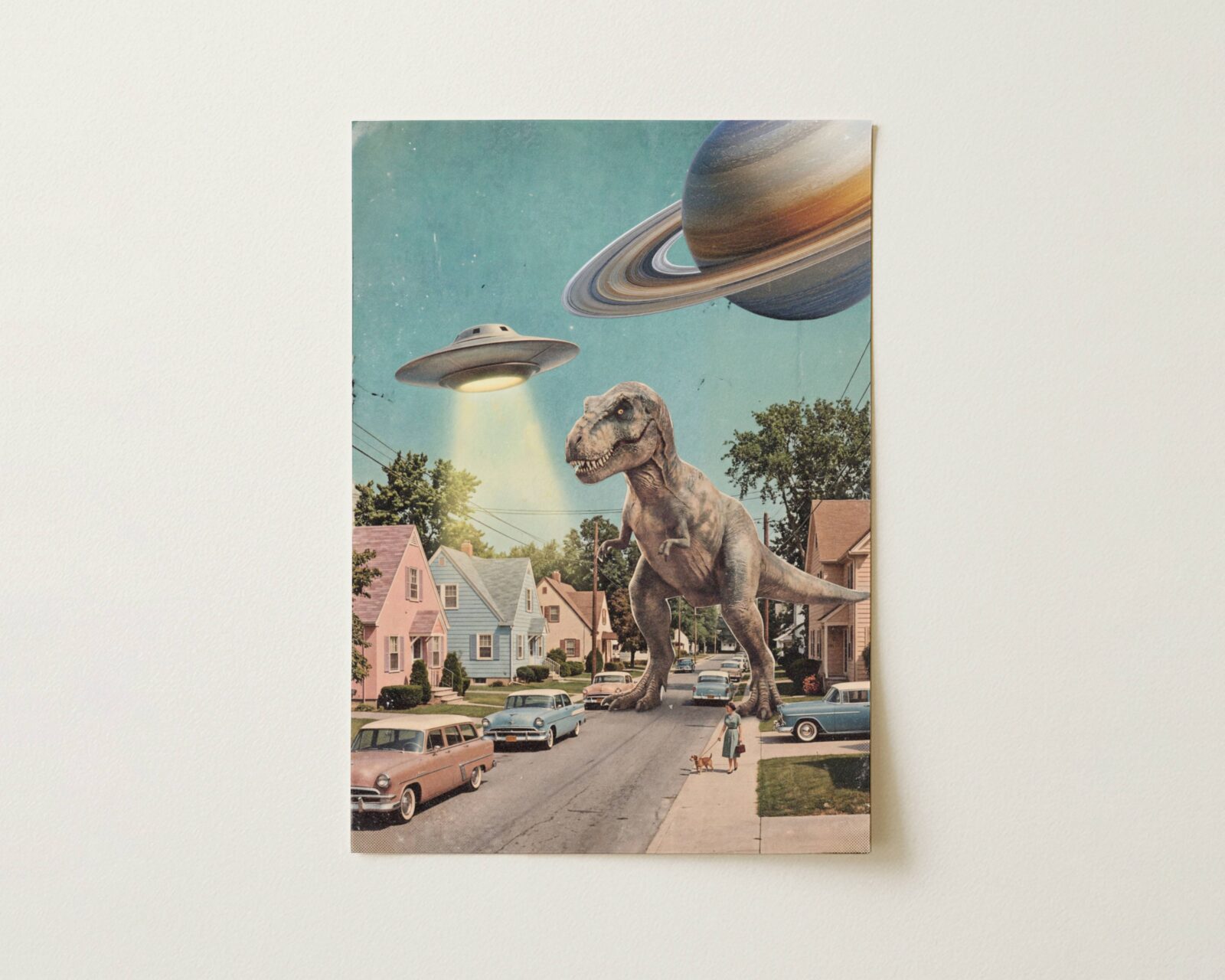 Flat print bold colourful vintage retro collage of a giant T-Rex on a 1950s American suburban street with a UFO hovering above pastel houses and Saturn in the top corner of a bright blue sky — high quality unframed flat poster print, ufoposter.com