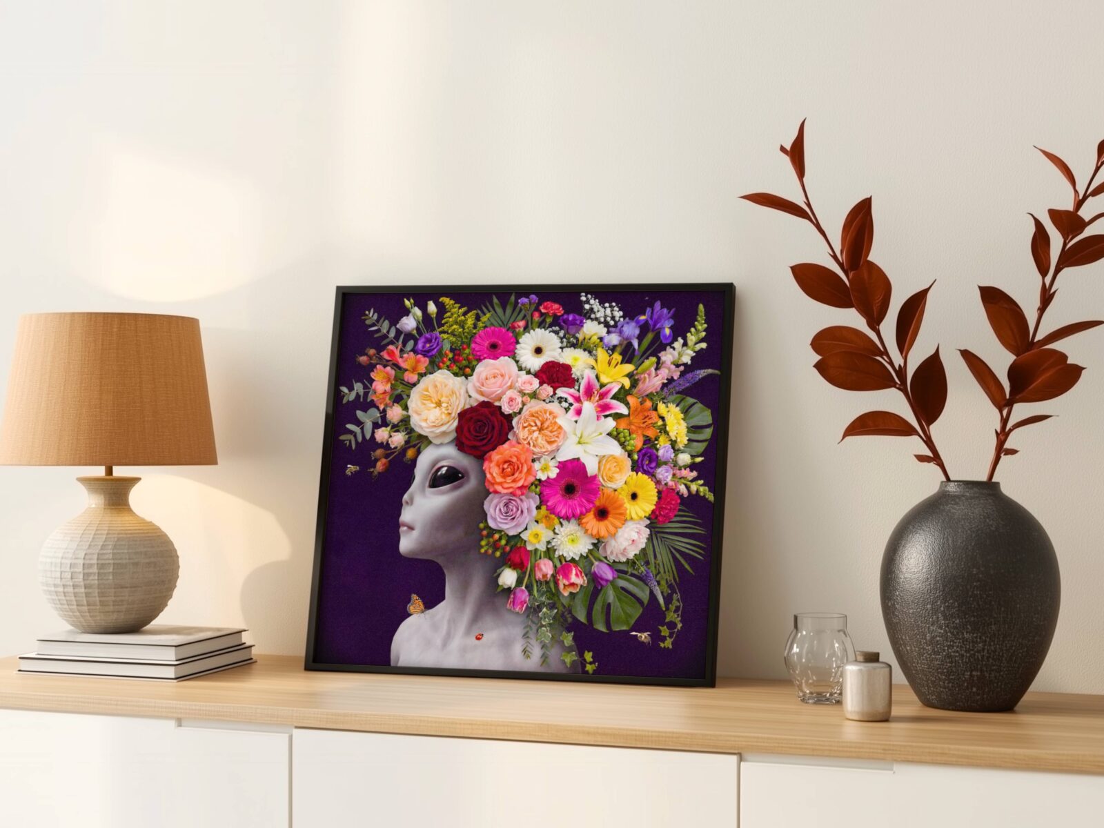 Vivid and radiant surreal portrait of a grey alien crowned with an extraordinary abundance of flowers — roses, gerberas, lilies, irises, tulips, snapdragons and monstera leaves — tumbling against deep dark purple with a monarch butterfly and ladybird — a bold and distinctive floral wall art print – unframed bold surreal alien flower poster, ufoposter.com